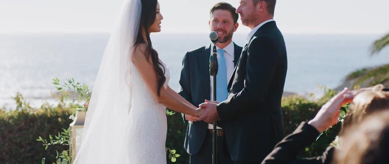 Jan and Brian holding hands through their vows, the ocean behind the altar.