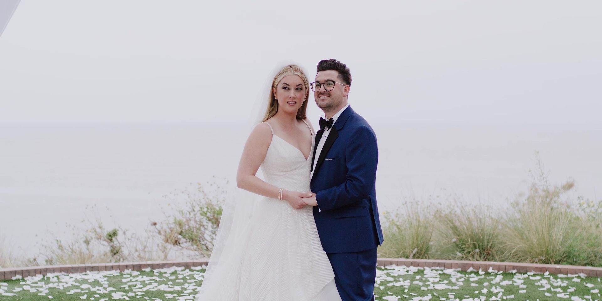 Josh and Gina together on the lawn at the bluff edge at Terranea Resort, the ocean behind them