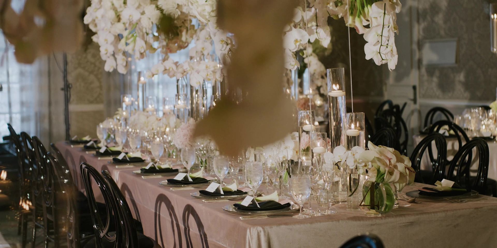 The reception tables, tall white arrangements standing above low candlelight and blush linen.