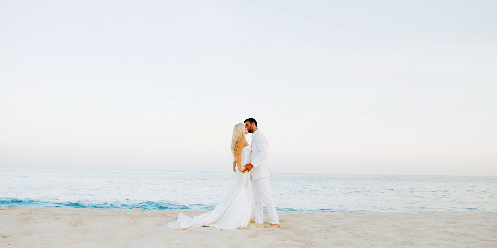 Bride and groom kissing on the sand at dusk in San Jose del Cabo, Mexico