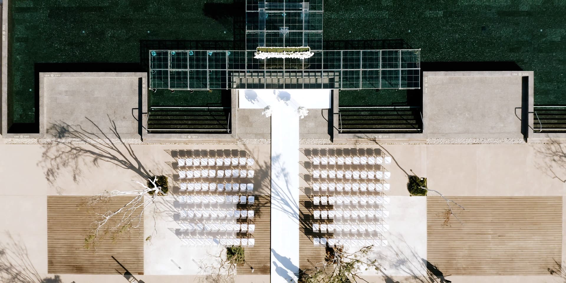Overhead aerial of a San Jose del Cabo wedding ceremony, the white aisle and rows of chairs beside the resort pool