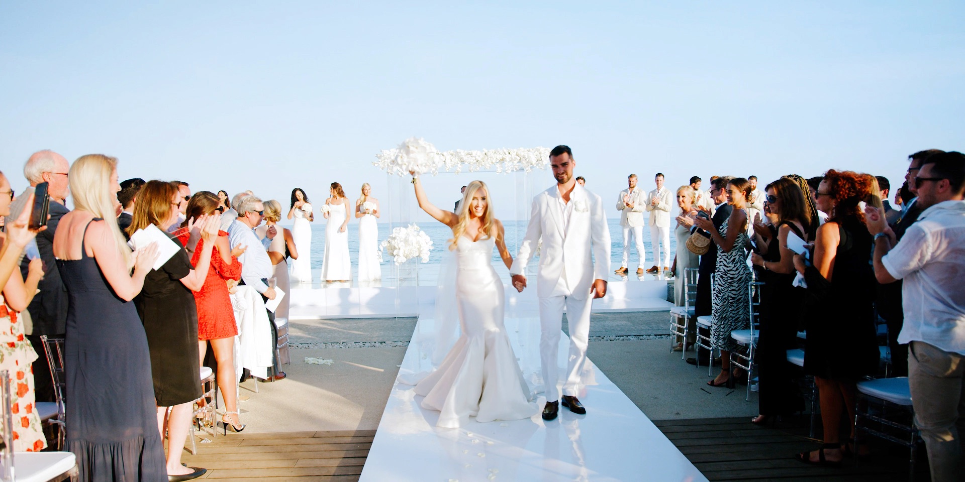 Wedding recessional down the white aisle at an oceanfront San Jose del Cabo ceremony, guests applauding