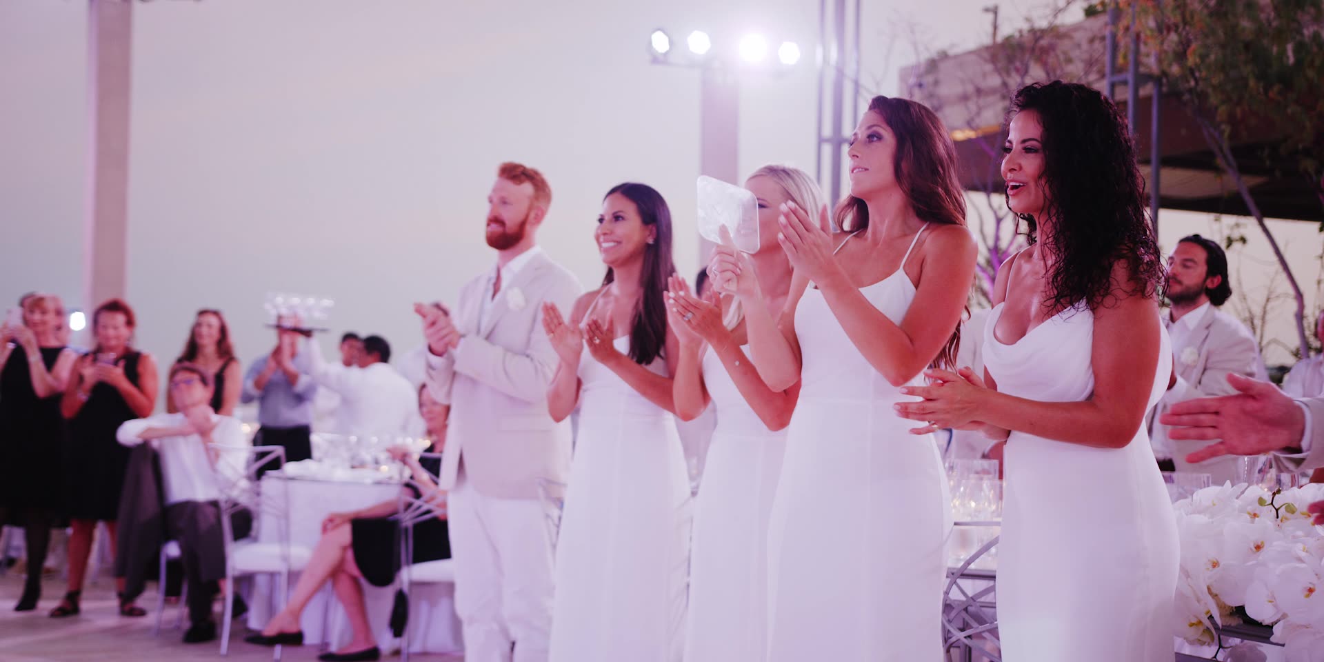 Guests in white applauding during the reception in Los Cabos