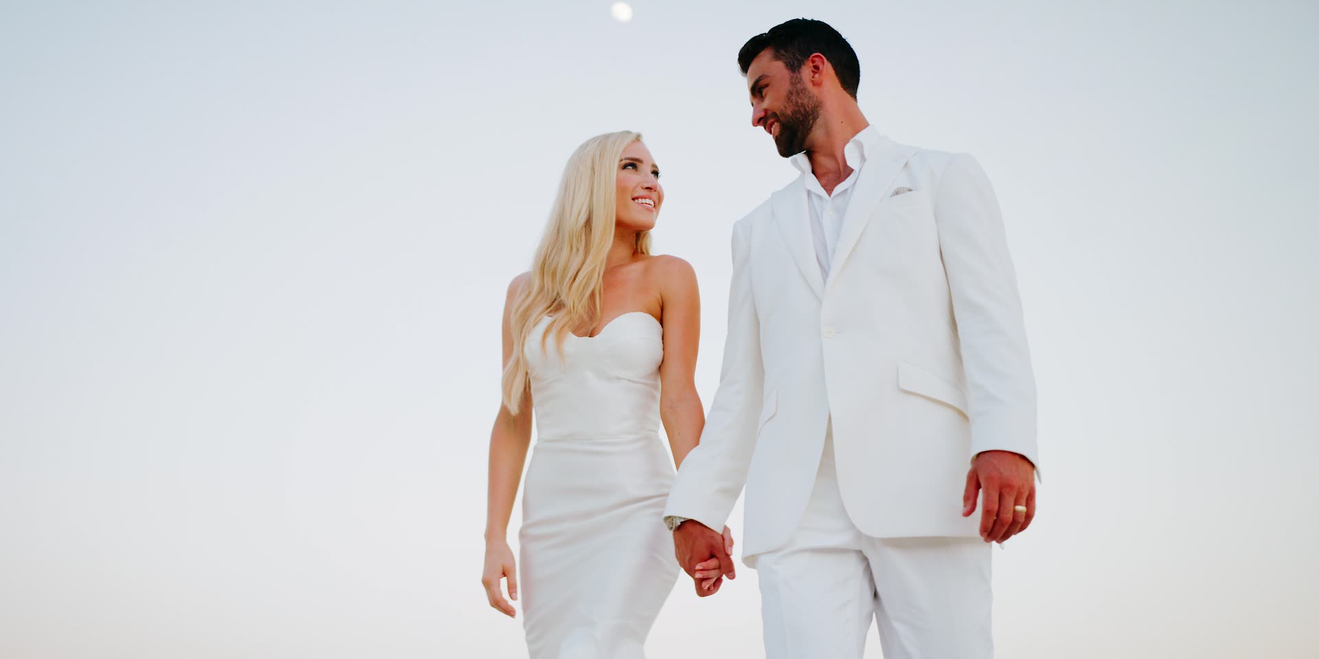 Justin and Kelsey walking together, both in white, in Los Cabos