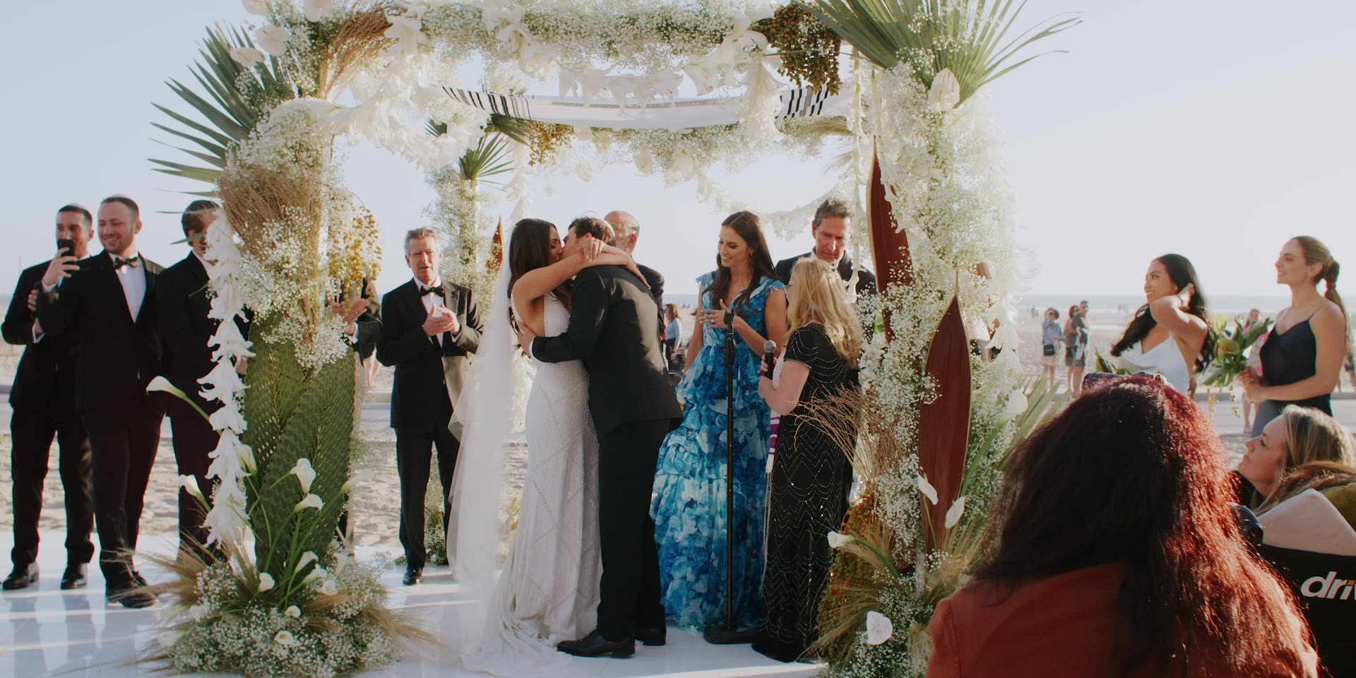 Jeremy and Lauren kissing beneath the chuppah of pampas and palm at Hotel Casa Del Mar