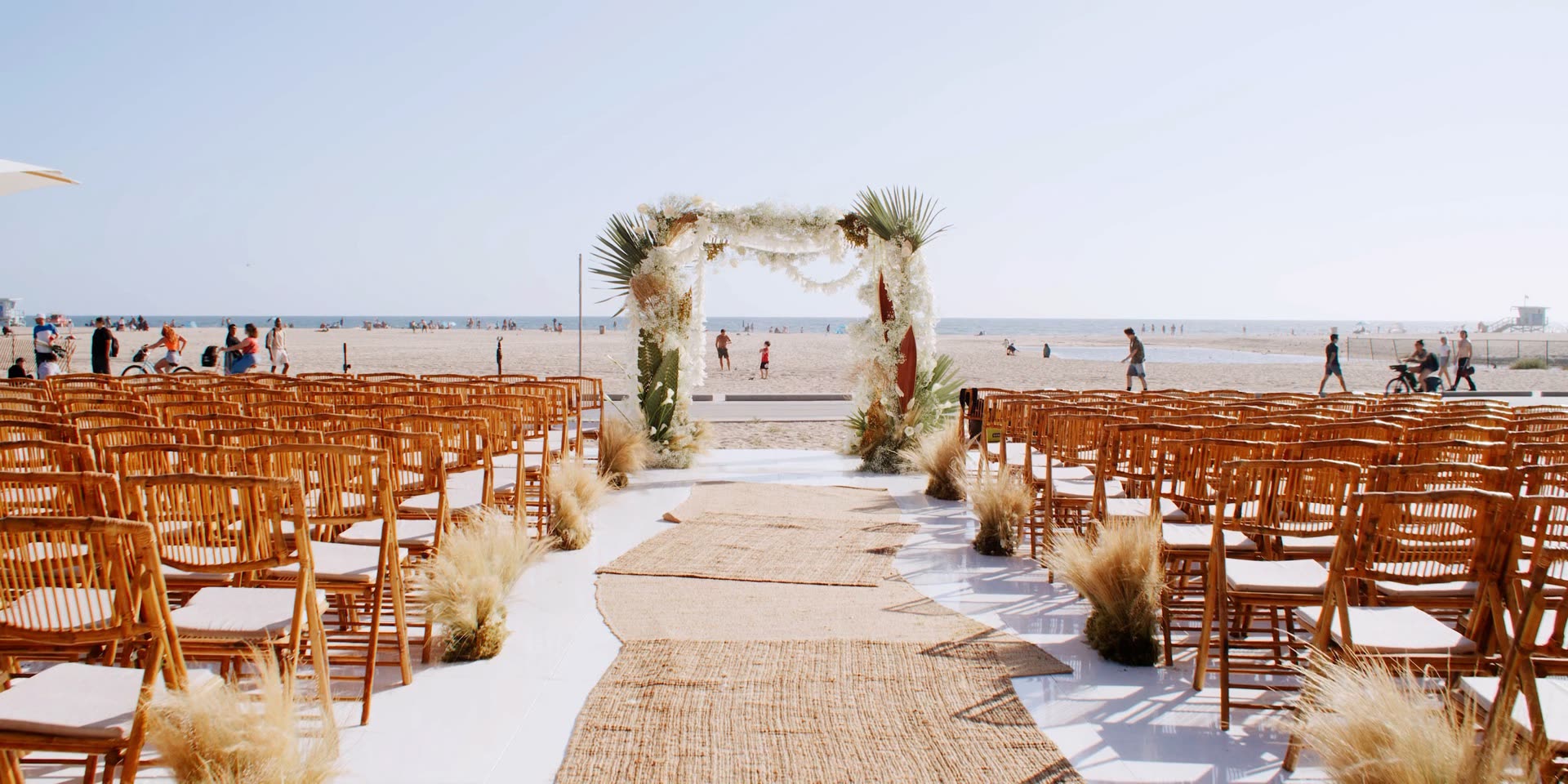 Beachfront wedding ceremony setup at Hotel Casa Del Mar, bamboo chairs and a floral arch facing the Pacific