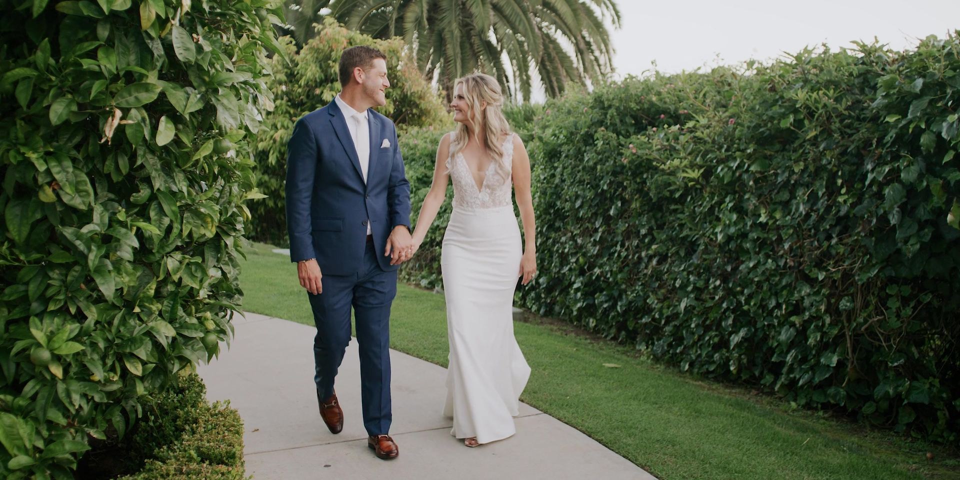 Justin and Mimi walking hand in hand along a hedged garden path at the Bel-Air Bay Club