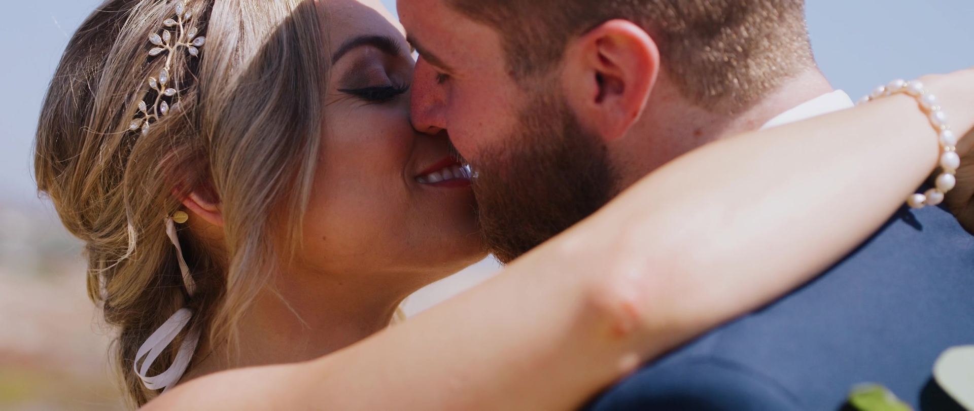 Josh and Shayna kissing, her hand with a pearl bracelet at the back of his neck.