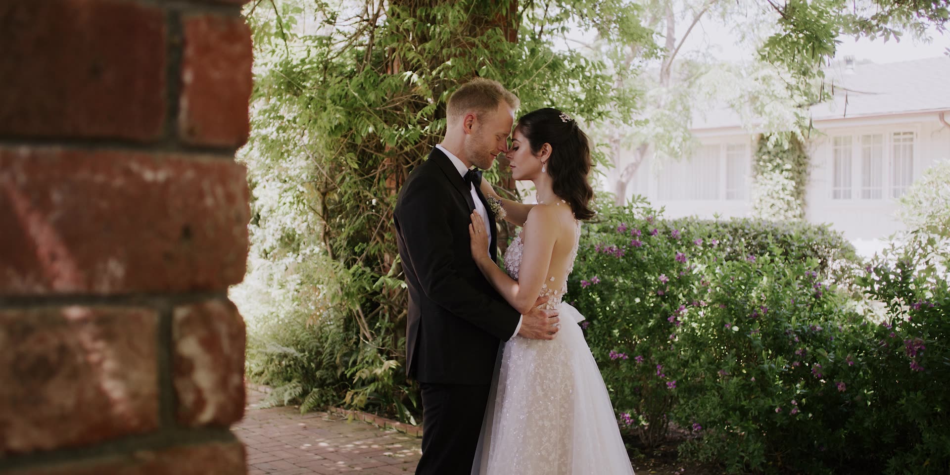 Kevin and Maya beside the brick wall in the gardens at Belmond El Encanto