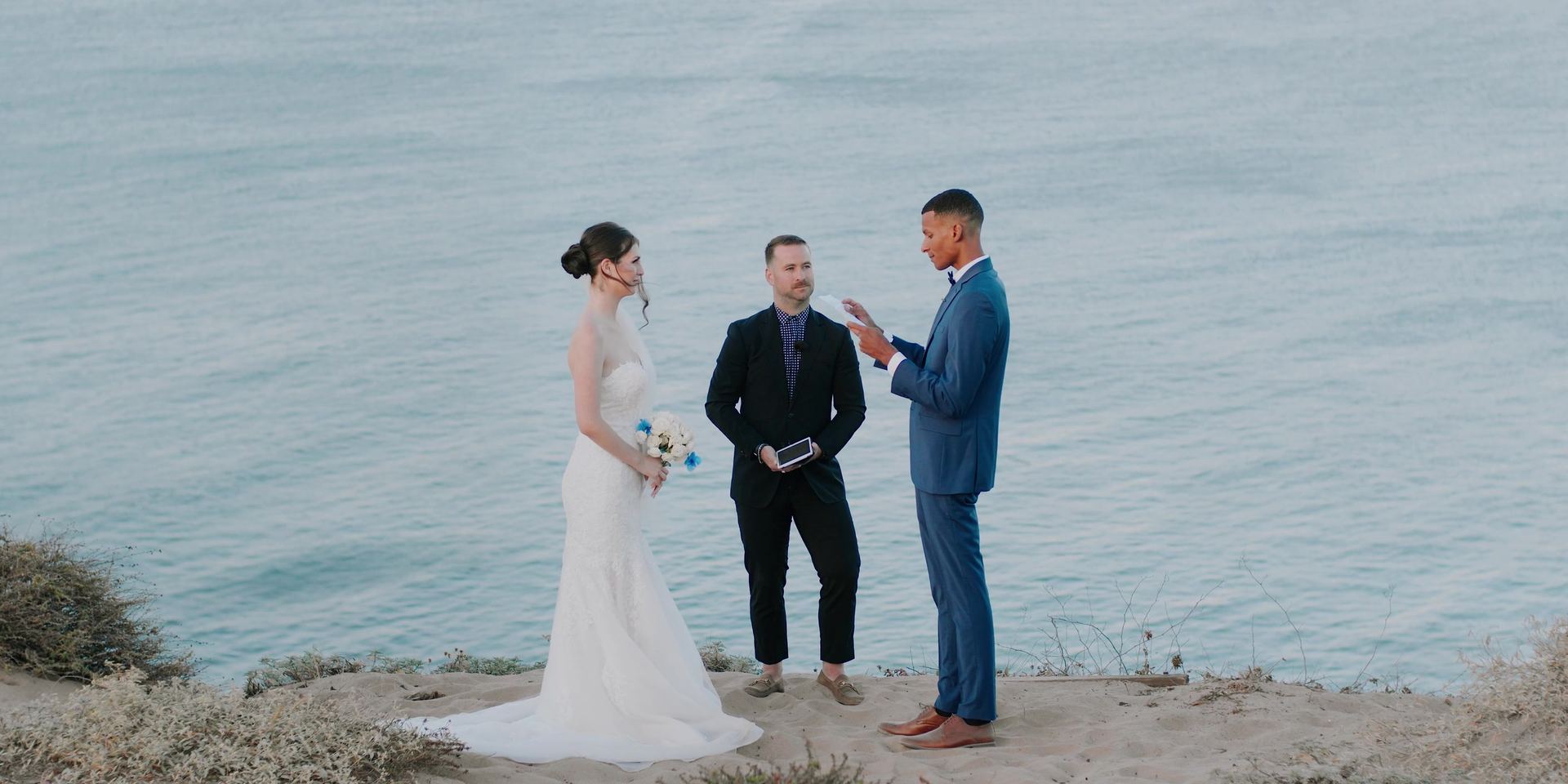 The ceremony on the cliff edge, the three of them standing above open water.