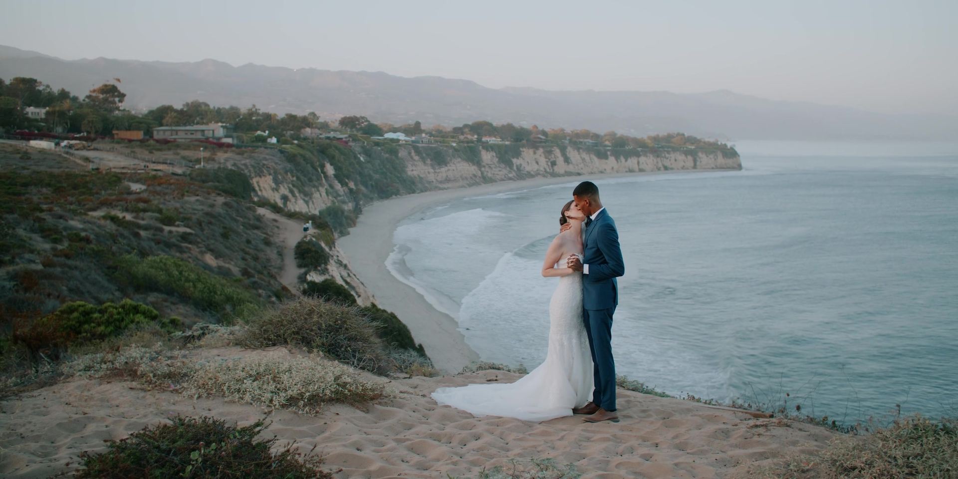 Lucas and Lindsey on the bluff above the cove, the coastline running away behind them.