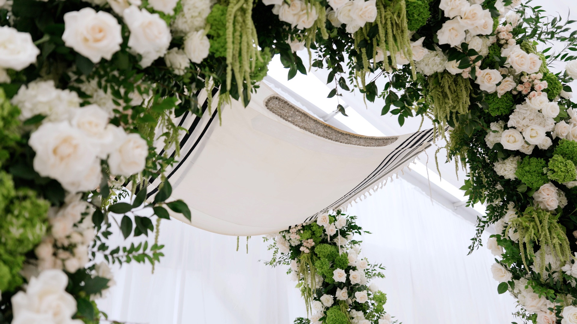 A floral chuppah draped with a tallit at a Jewish wedding ceremony in Beverly Hills