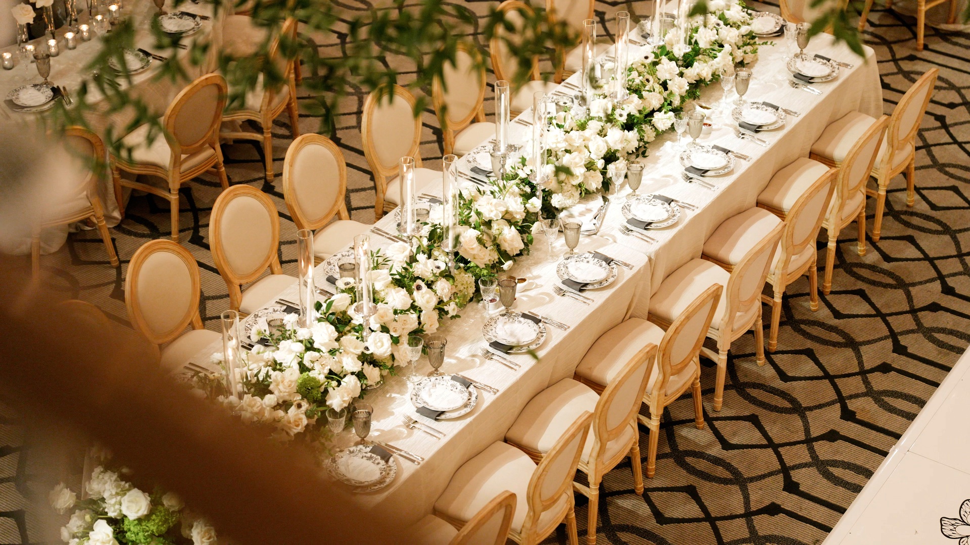 A wedding reception table at The Maybourne Beverly Hills, white roses and taper candles running the length of a long banquet table