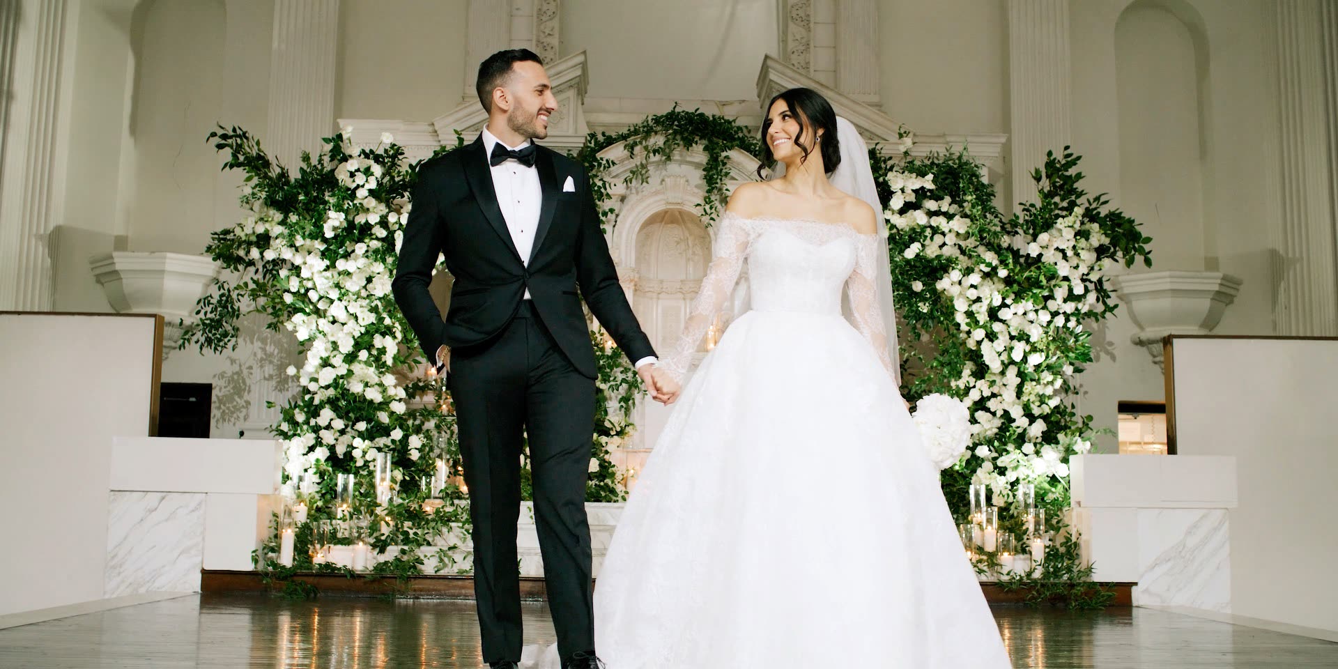 Bride and groom before the white floral altar at Vibiana in downtown Los Angeles