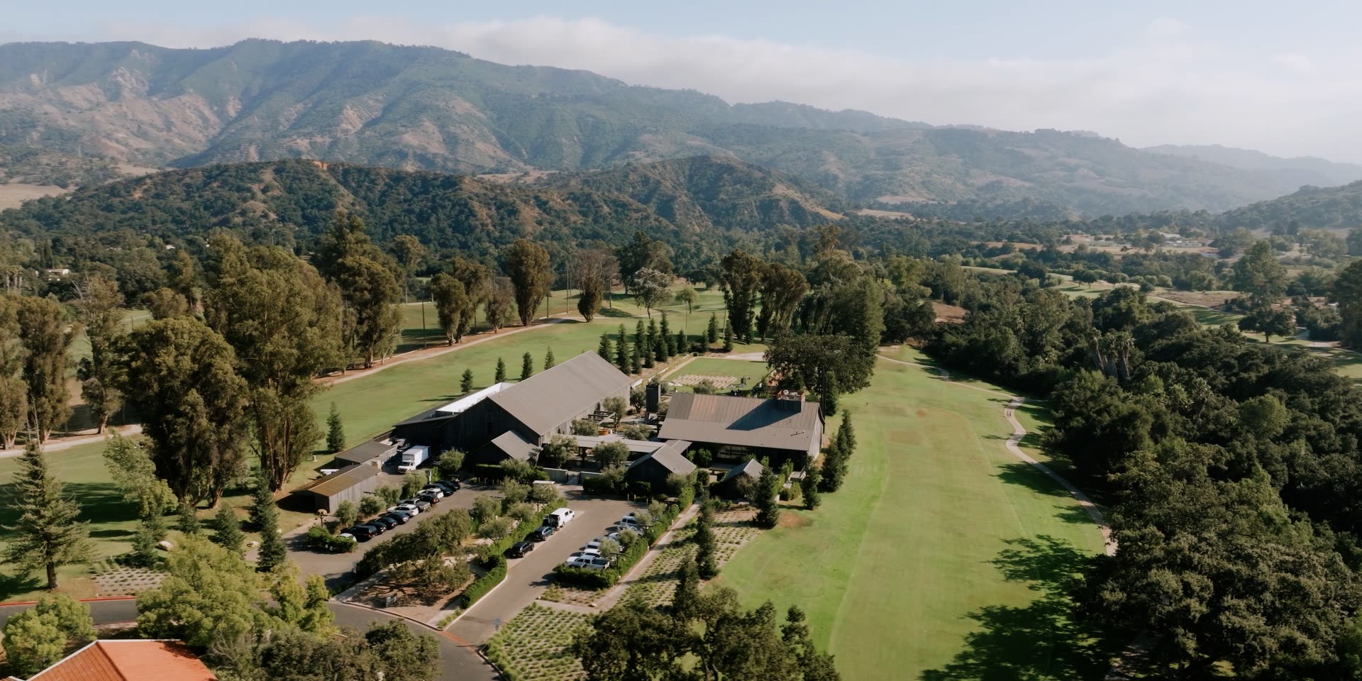 Aerial drone view of the Ojai Valley Inn Farmhouse wedding venue set in the valley with the Topa Topa mountains behind