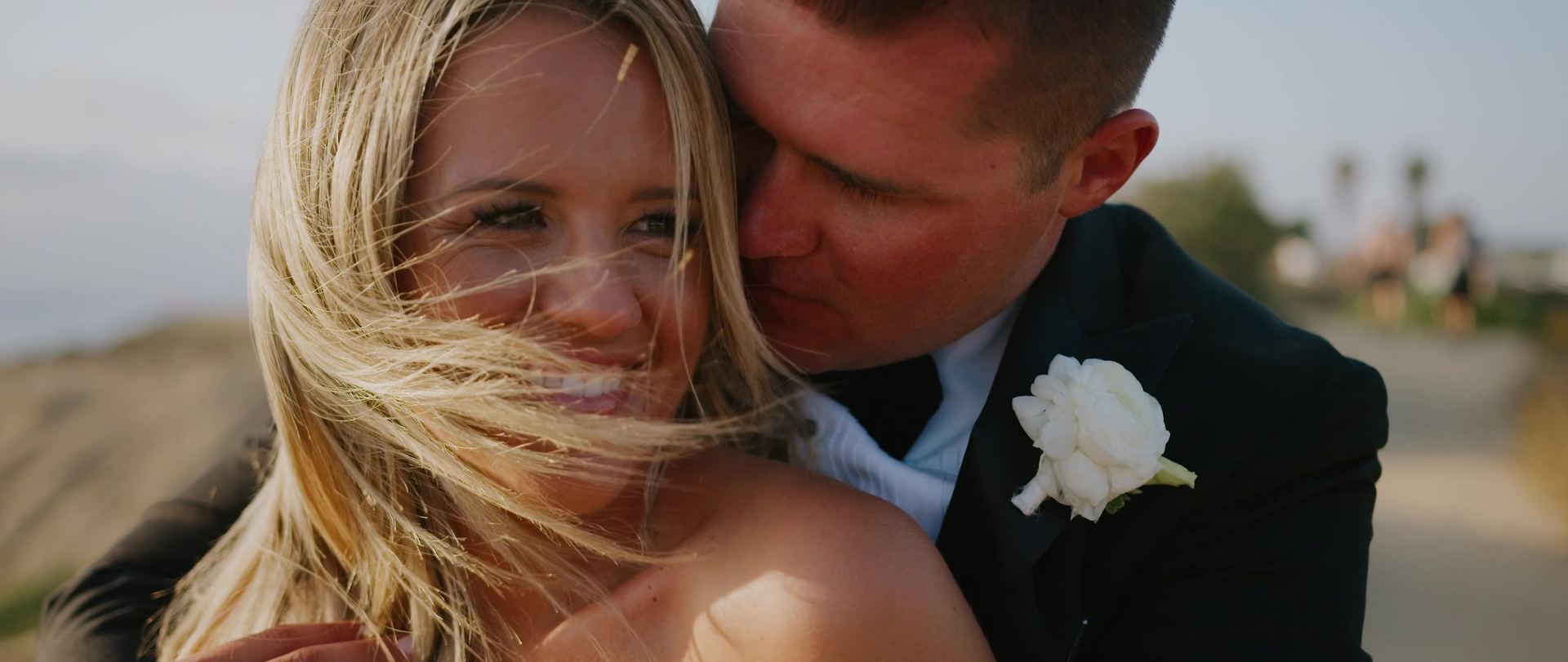 Nick kissing Paige's cheek out on the bluff, her hair blowing across the frame.