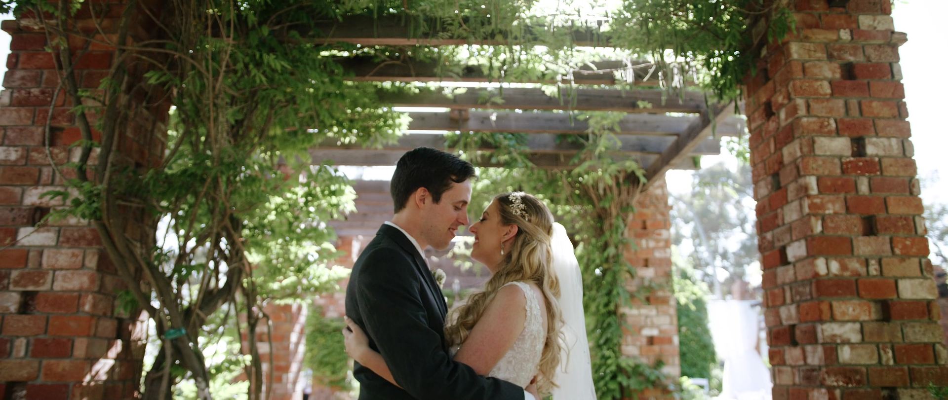 Ryan and Mandi kissing under the vine-covered pergola.