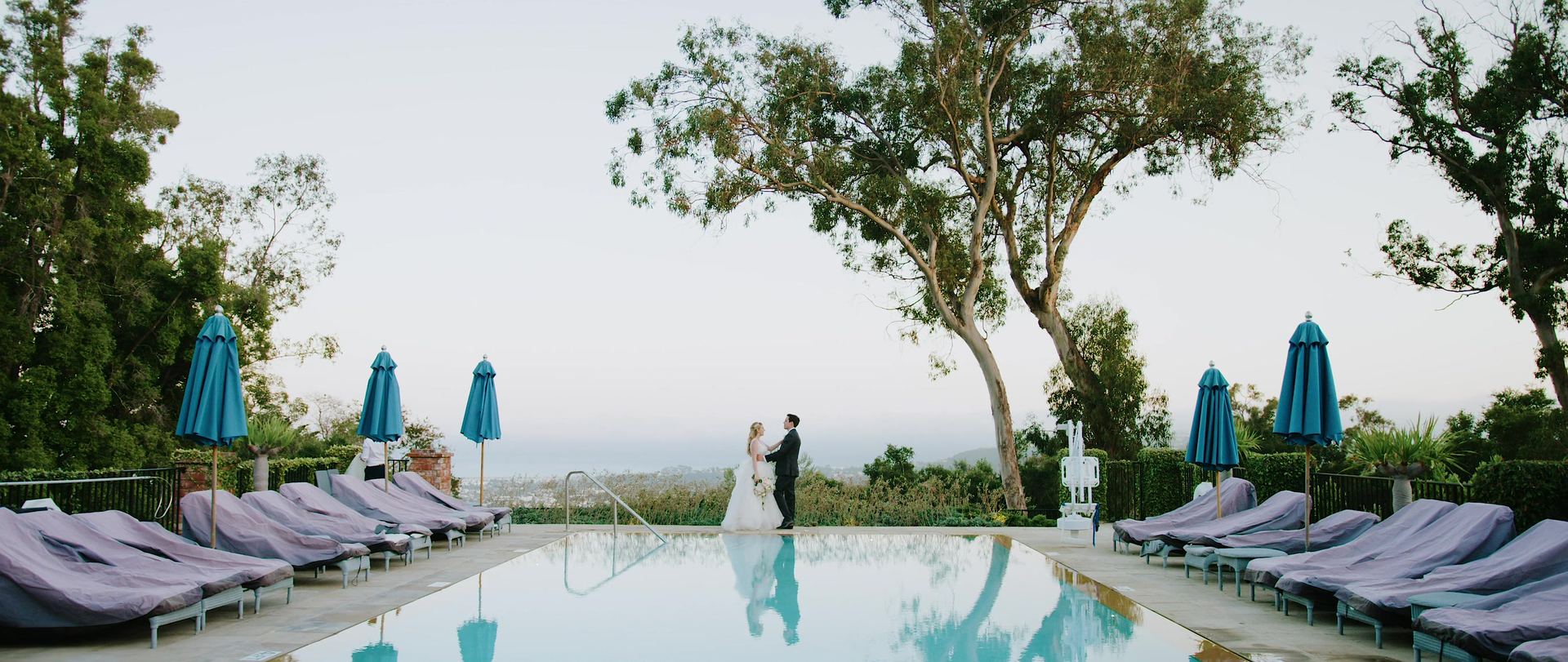 The pool terrace, the couple at the far end beneath the eucalyptus, the town spread out below under a pale sky.