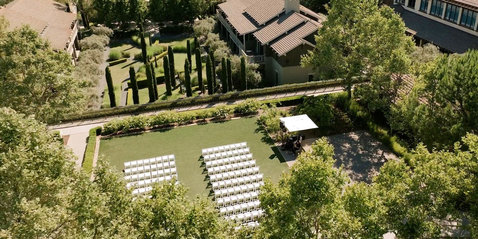 Aerial view of a Rosewood Sand Hill wedding ceremony set on the garden lawn with cypress trees and the resort's cedar lodges