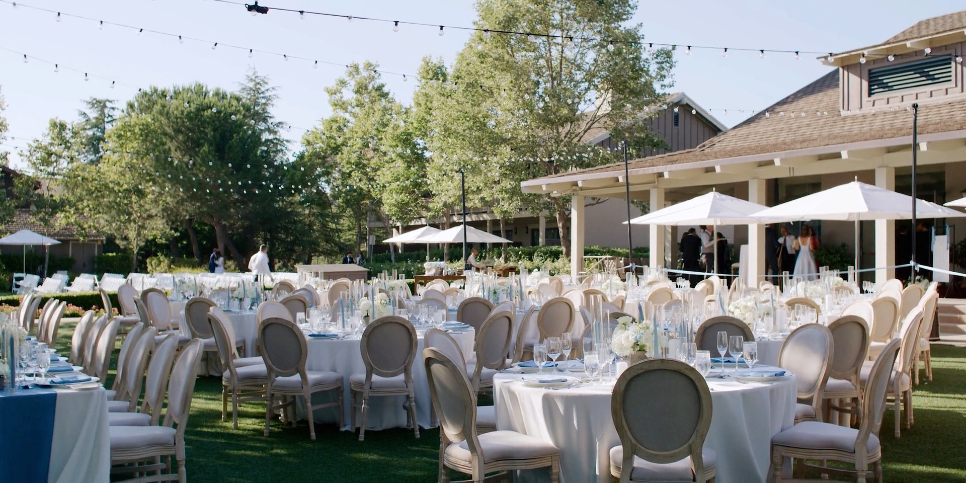 Rosewood Sand Hill wedding reception on the lawn, round tables beneath strings of light and white umbrellas