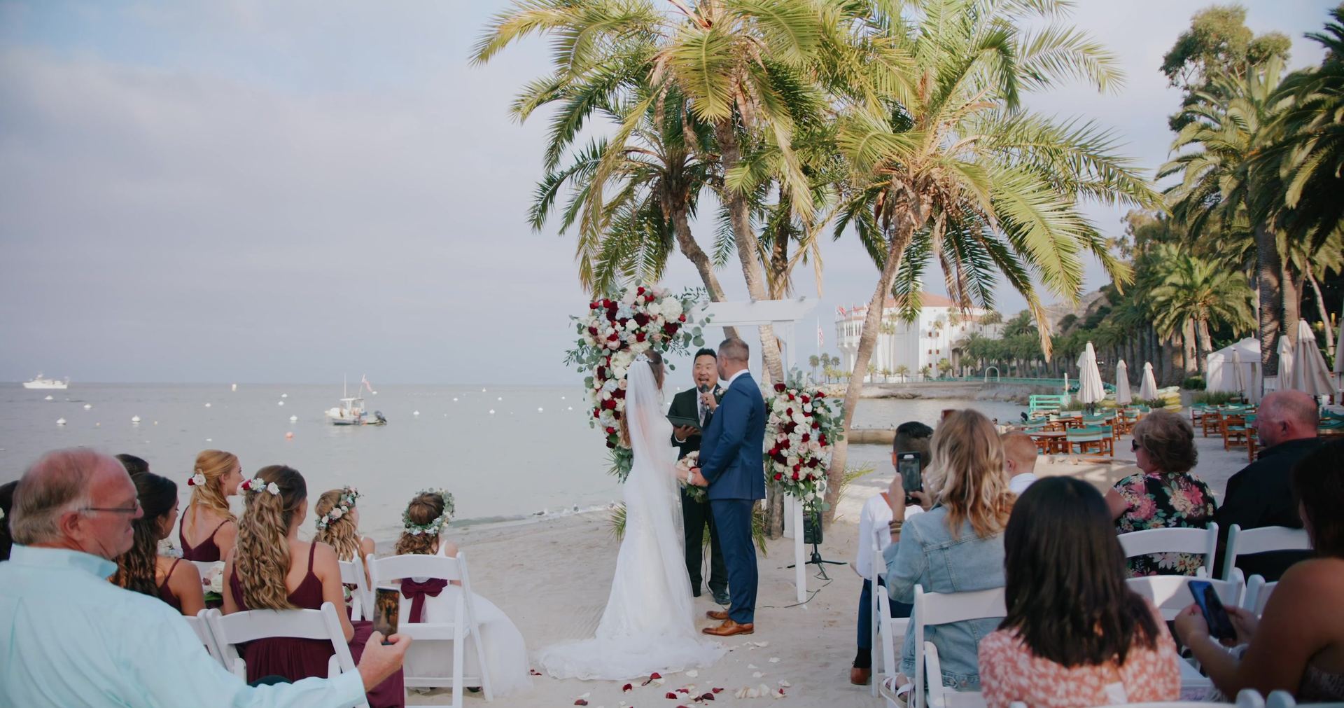 The ceremony on the waterfront, guests seated beneath the palms.
