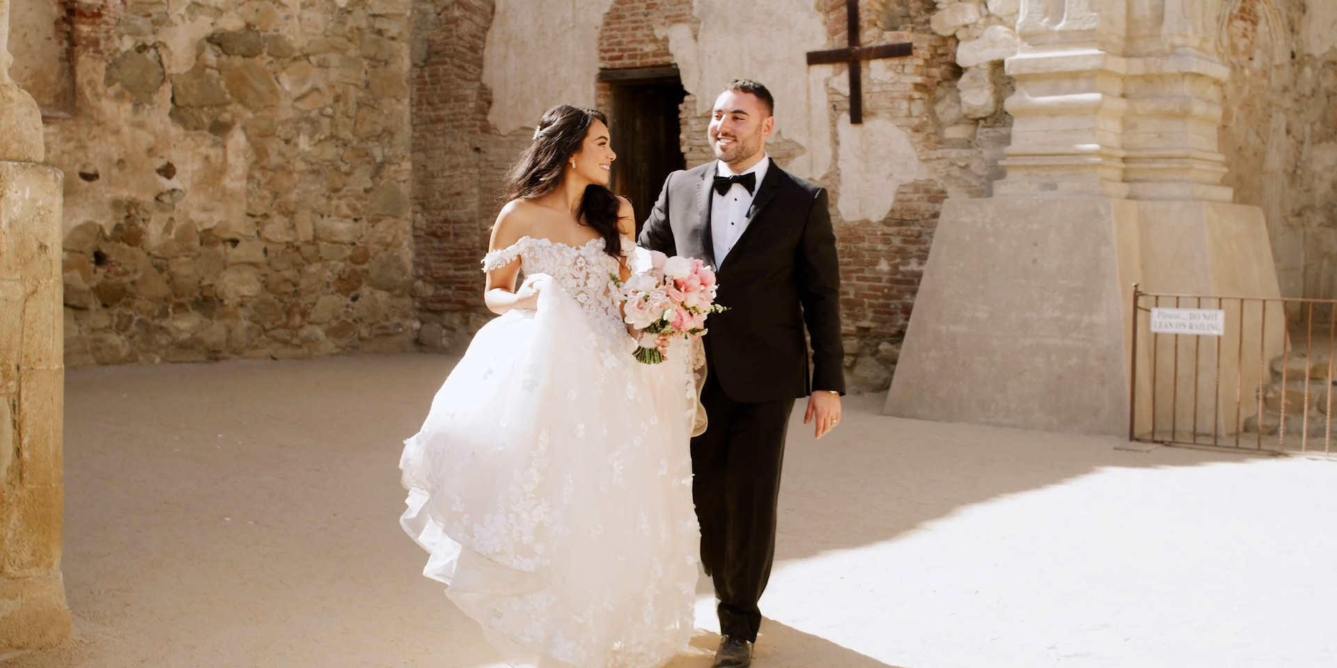 Bride and groom walking through the stone ruins of Mission San Juan Capistrano during their portrait session