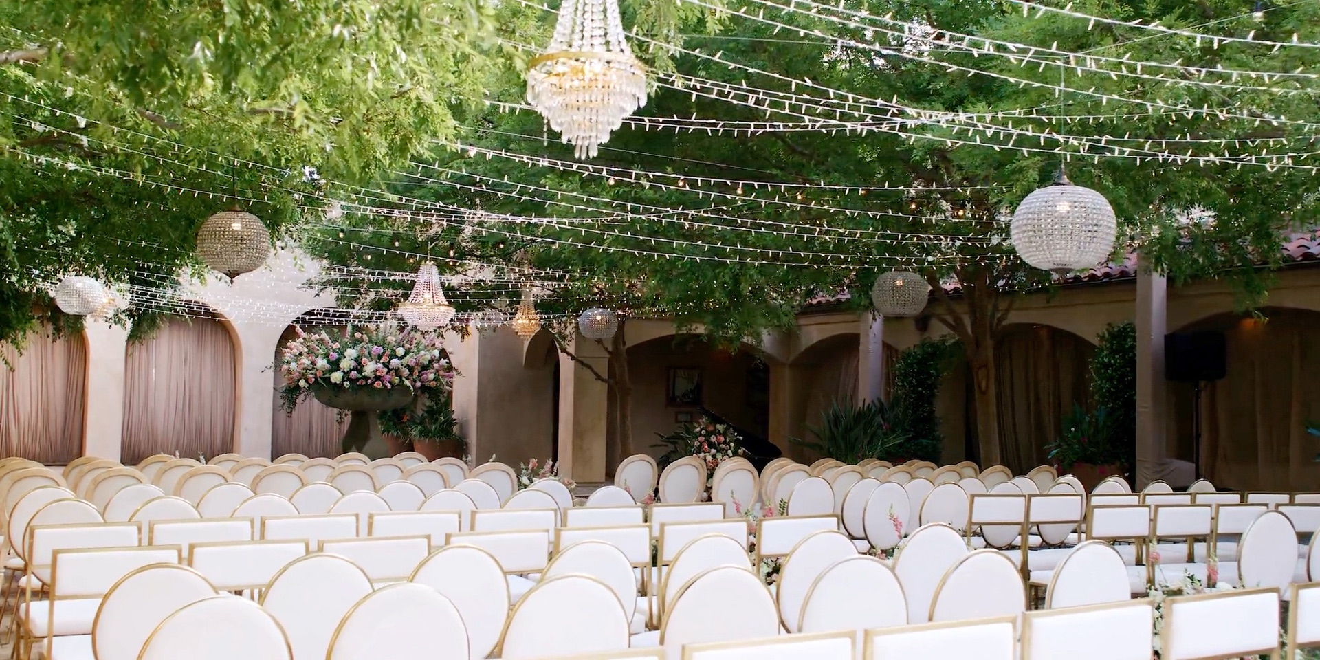 Serra Plaza wedding ceremony set with gold and white chairs beneath the string-light and crystal chandelier canopy